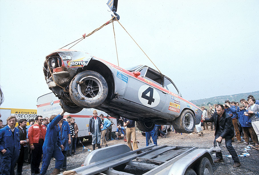A crane moves Jacky Ickx' crashed BMW on a tow-away truck