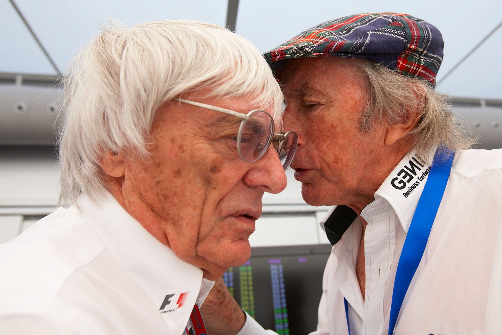 Sir Jackie Stewart whispers into Bernie Ecclestone's ear