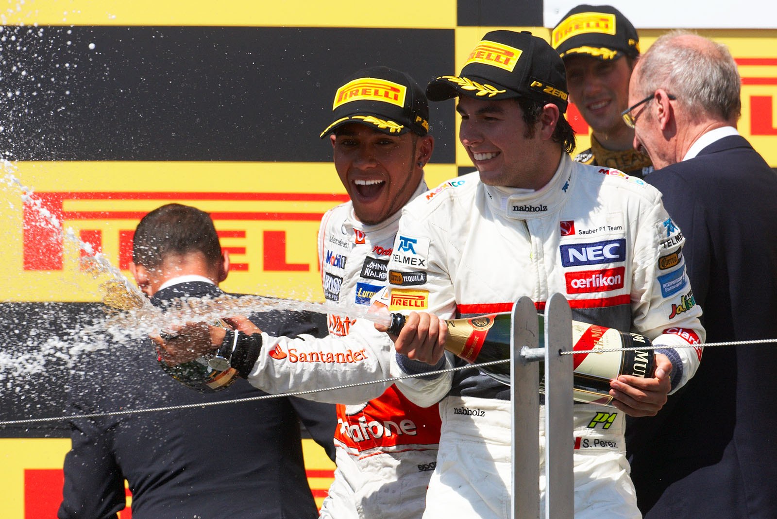 Race winner Lewis Hamilton of McLaren Mercedes and Sauber's third placed Sergio Perez spray champagne on the podium